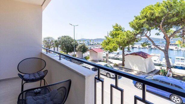 A balcony with a chair, a table, a view of a marina with boats, and a tree. - Boutique Rooms Rogovo (Sveti Filip i Jakov)