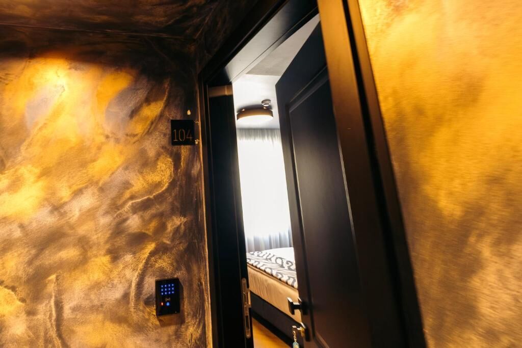 A room with a bed, a door, and a wall with a textured pattern.