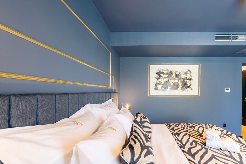 A hotel room with a bed, a headboard, a framed picture on the wall, and a window.