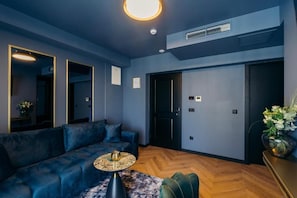 A modern living room with a blue sofa, a round coffee table, and a large mirror.