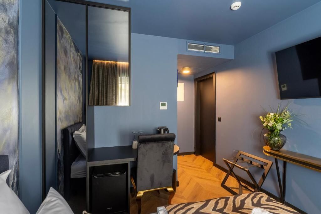 Camera d'albergo compatta con un letto, una scrivania, una sedia, un angolo cottura e una televisione.