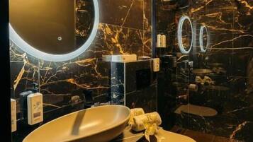 A modern bathroom with a large oval sink, two round mirrors, and a marble wall.