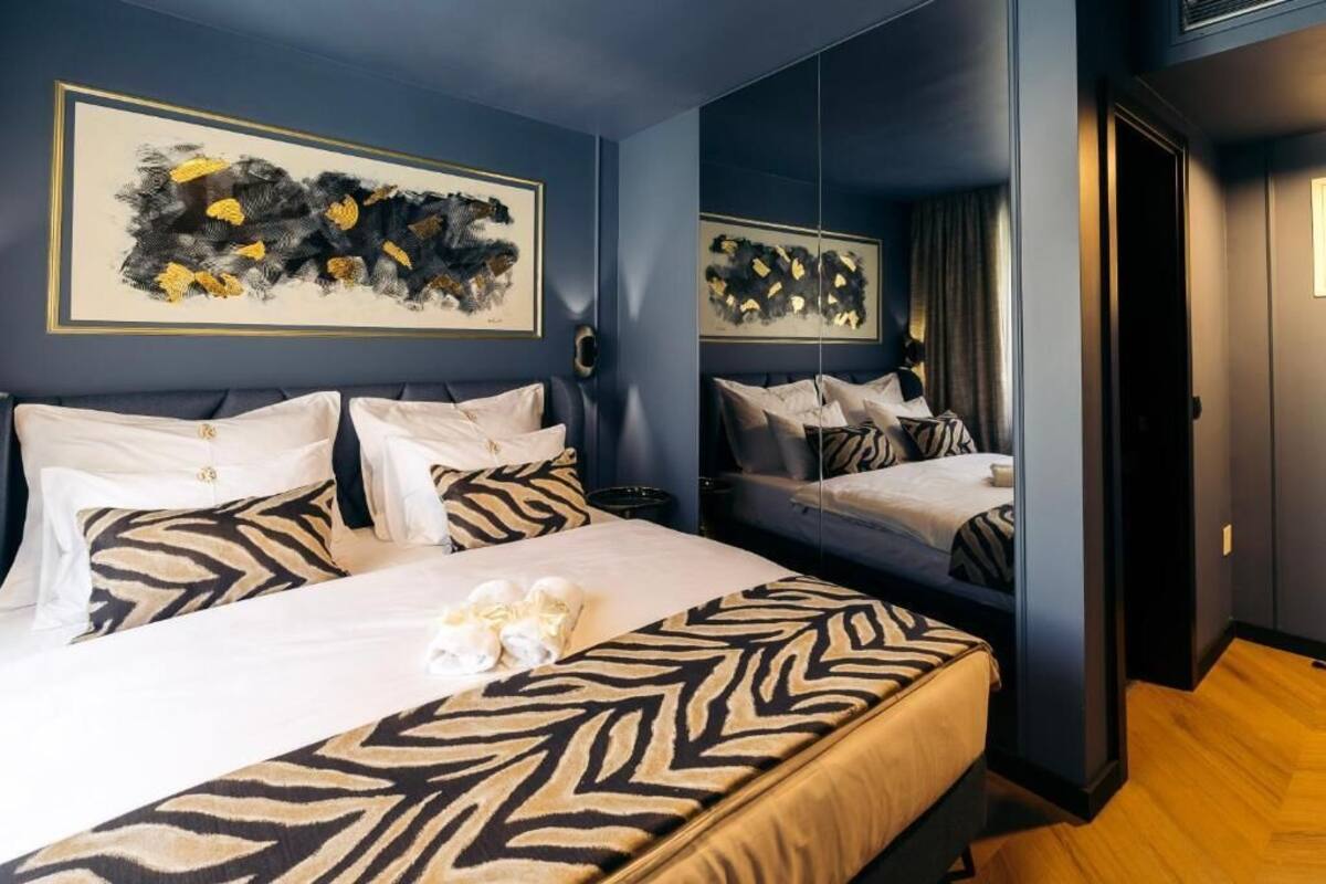 Ein Hotelzimmer mit zwei Betten, zebra-gemusterten Laken, abstrakter Kunst an den Wänden und Holzboden.
