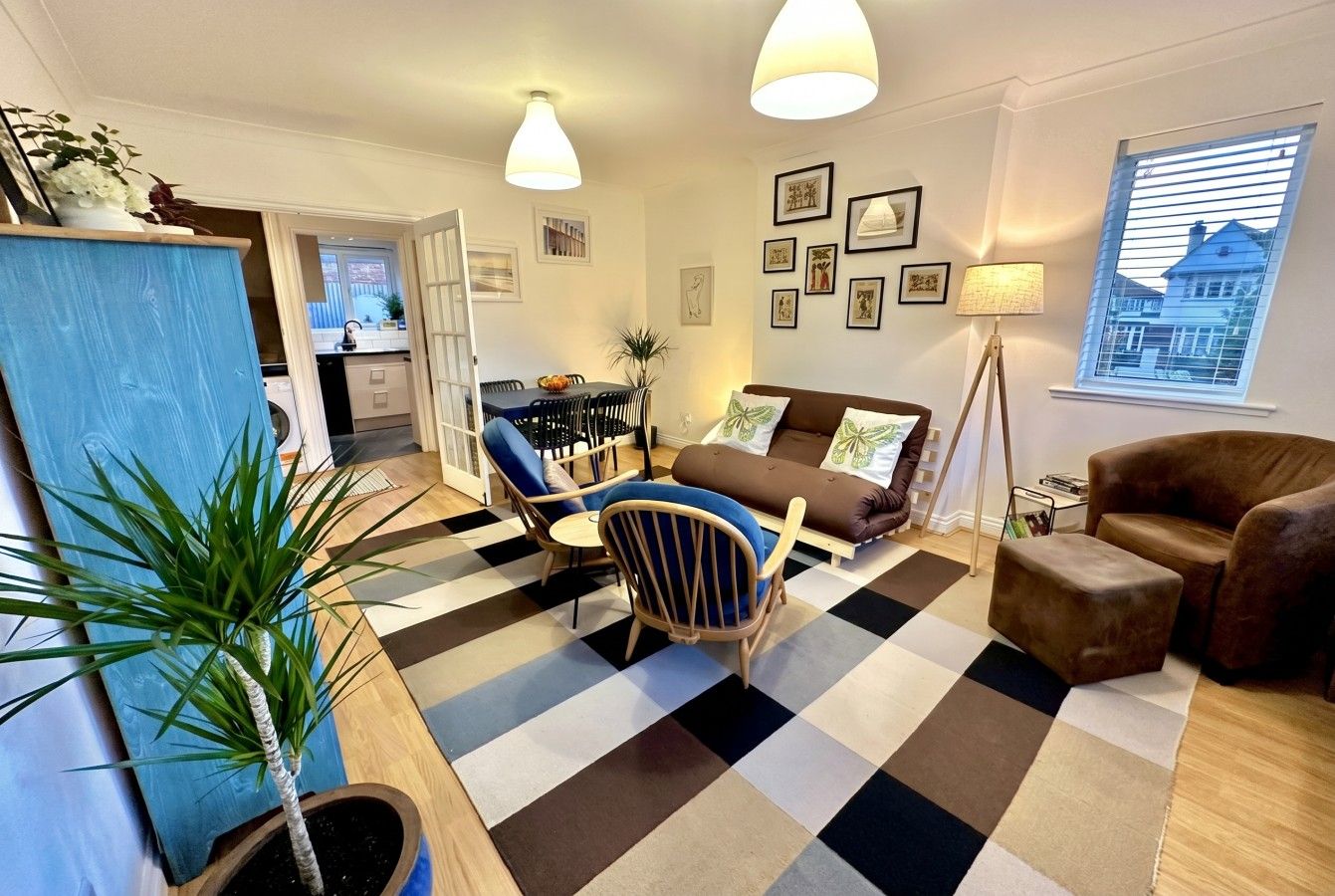 A living room with a checkered floor, a sofa, a coffee table, and a dining area with chairs and a table.