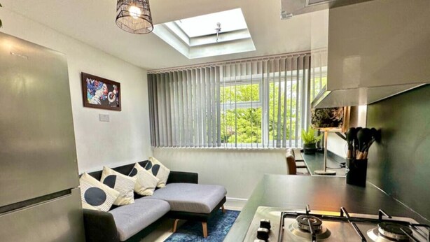 A compact kitchen with a gas stove, a built-in oven, and a window with blinds. - Spacious 2-bedroom flat with parking, near top event venues (Greater London)