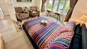 A bedroom with a large bed, a desk, a chair, and a window with curtains. - Spacious 2-bedroom flat with parking, near top event venues (Greater London)