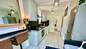A modern kitchen with a central island, bar stools, a sofa, and a large mirror. - Spacious 2-bedroom flat with parking, near top event venues (Greater London)