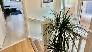 A hallway with a wooden floor, a potted plant, a framed artwork on the wall, and a window with frosted glass. - Spacious 2-bedroom flat with parking, near top event venues (Greater London)