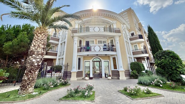 A multi-story building with a central entrance, balconies, and surrounding greenery. - Menada Messembria Palace Apartments (Sunny Beach)