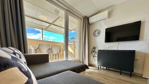 A hotel room with two sofas, a flat-screen TV, and a balcony with chairs. - Menada Messembria Palace Apartments (Sunny Beach)