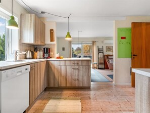 A modern kitchen with wooden cabinets, a built-in island, and pendant lighting. - "Paule" - 1.3km from the sea by Interhome (Læsø)