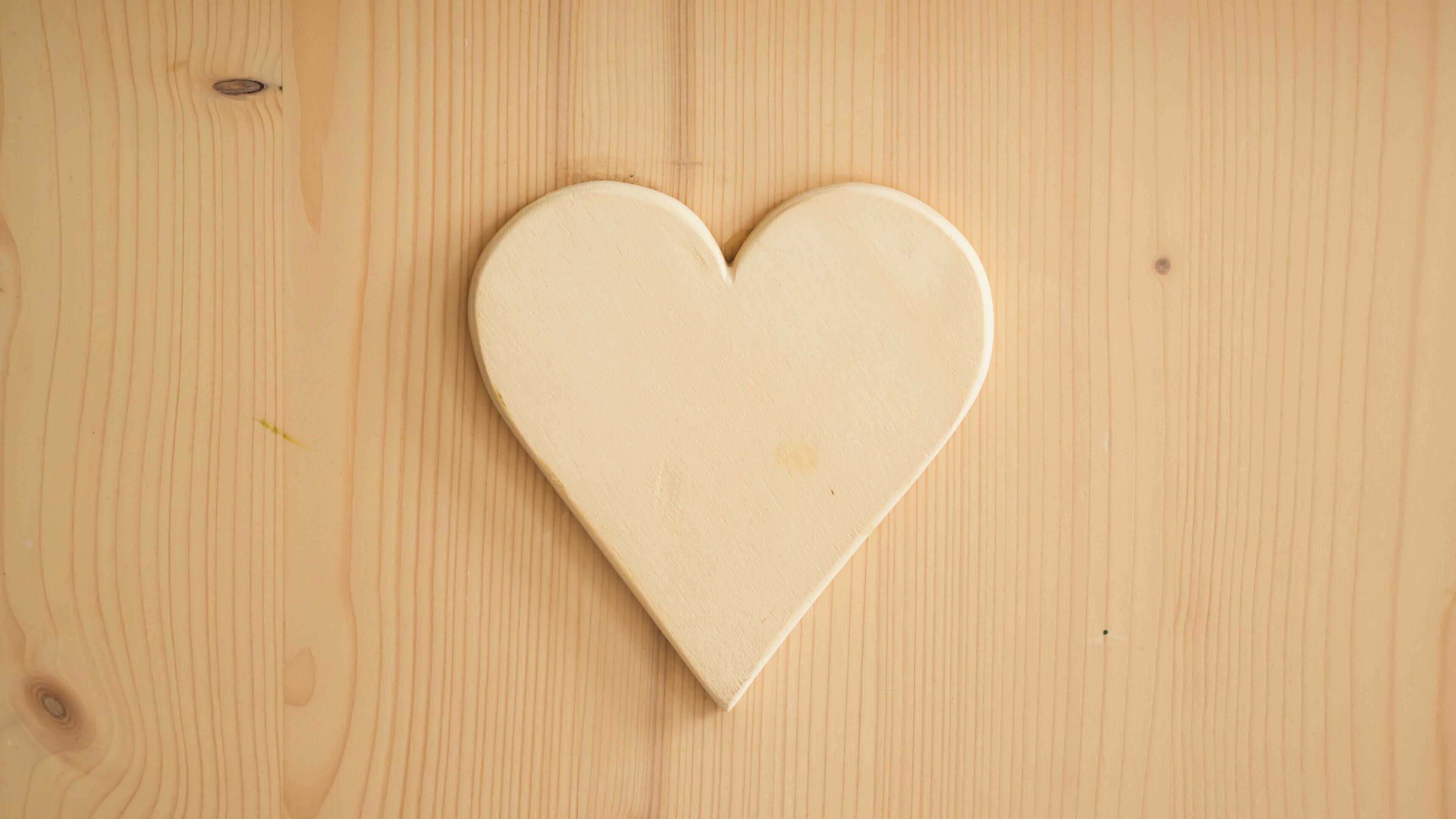 A wooden heart-shaped object on a wooden surface.