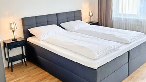 Un dormitorio moderno con una cama grande, dos mesitas de noche y un ventanal con cortinas.