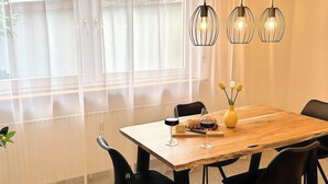 Un comedor con mesa de madera, sillas negras y lámparas colgantes.