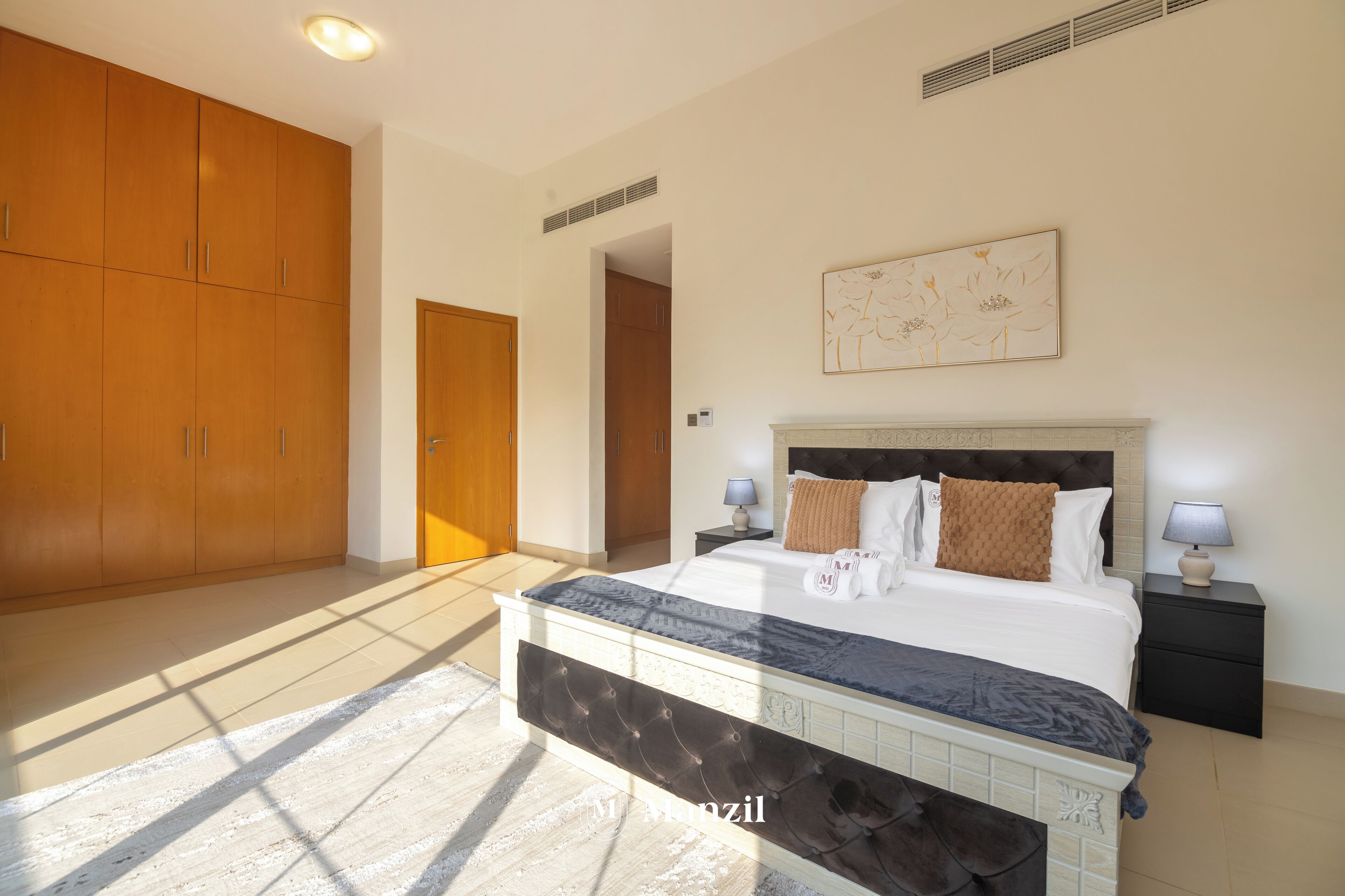 Quarto com cama grande, guarda-roupa de madeira e um quadro na parede.