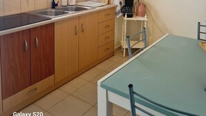 Une cuisine de taille réduite, avec des meubles de rangement en bois, un évier et une fenêtre.