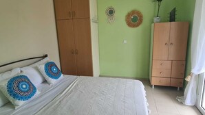 Une chambre à coucher comprenant un lit, deux armoires, un luminaire suspendu et des éléments de décoration murale.