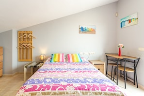 Ein Schlafzimmer mit einem Bett, einem Schreibtisch, einem Sessel, einem Holzschrank und einem Wandregal.