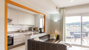 Een moderne keuken met witte kasten, een bruine leren bank en een eethoek met een tafel en stoelen.