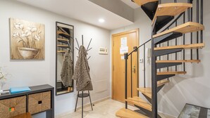 Een modern interieur met een spiltrap, een spiegel, een houten console en een wandkunstwerk.