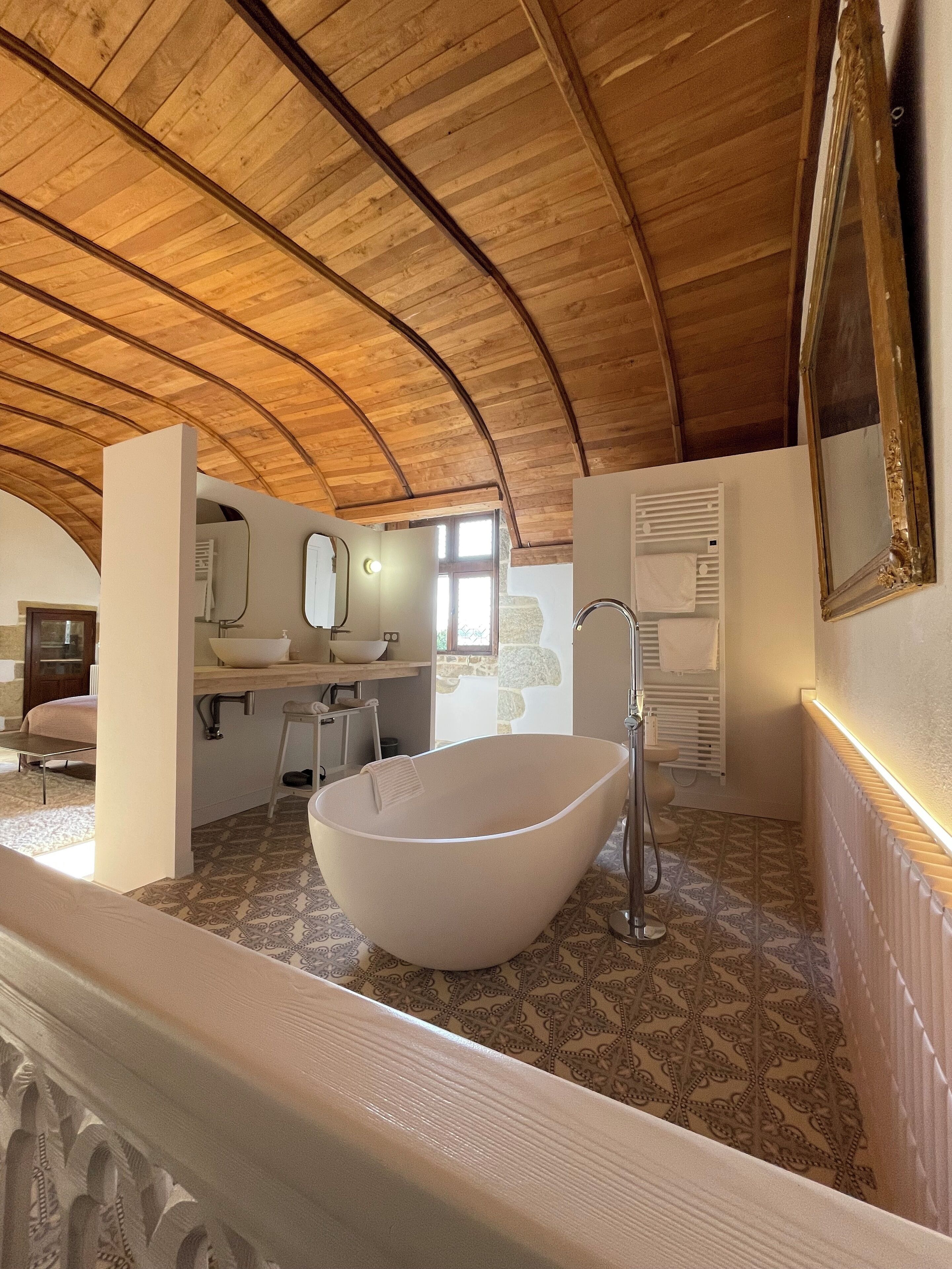 Un baño espacioso con una bañera independiente, un tocador con espejo y una zona de ducha.