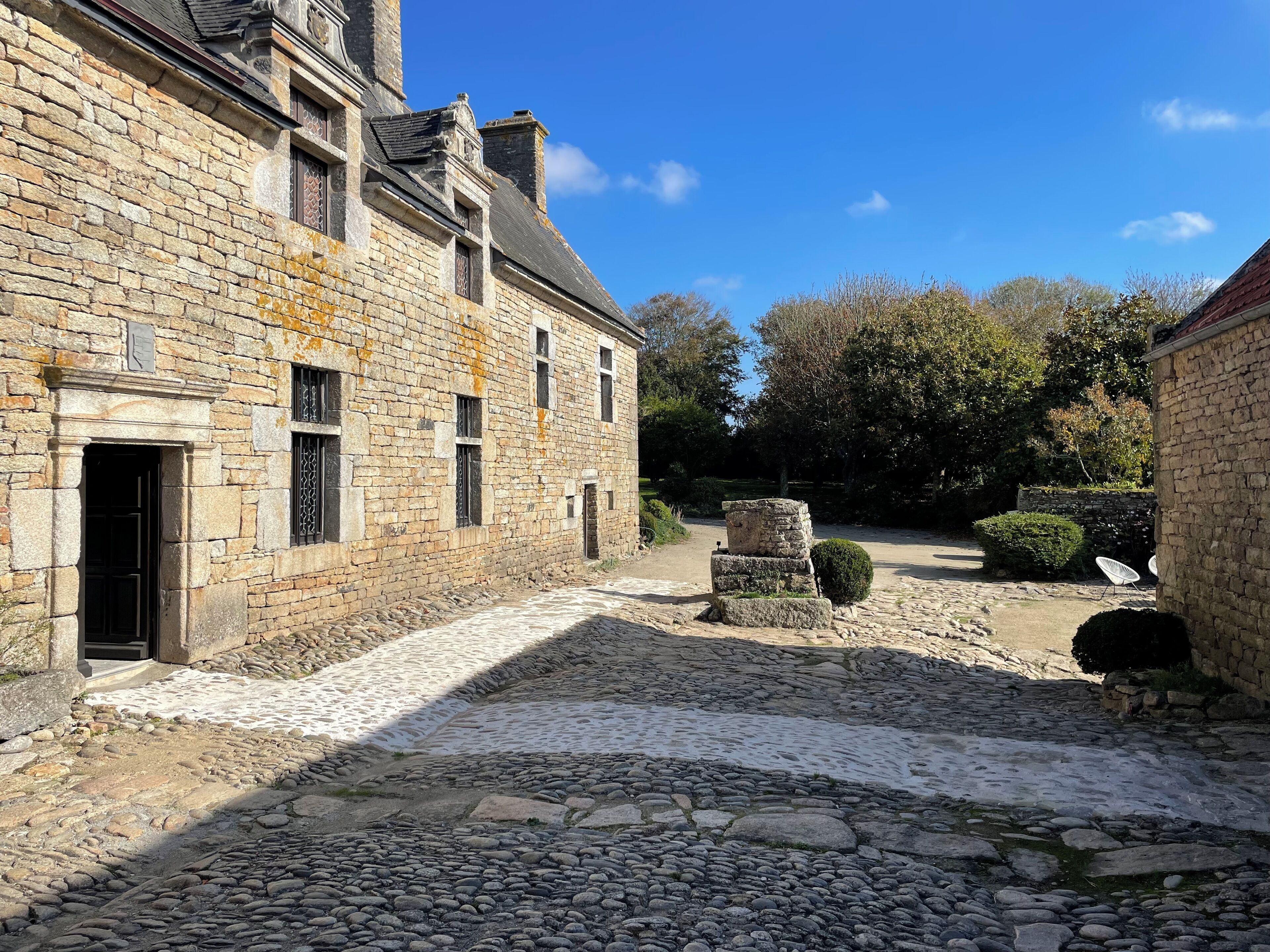 Un patio con senderos de adoquines, edificios de piedra y una pequeña construcción de piedra.