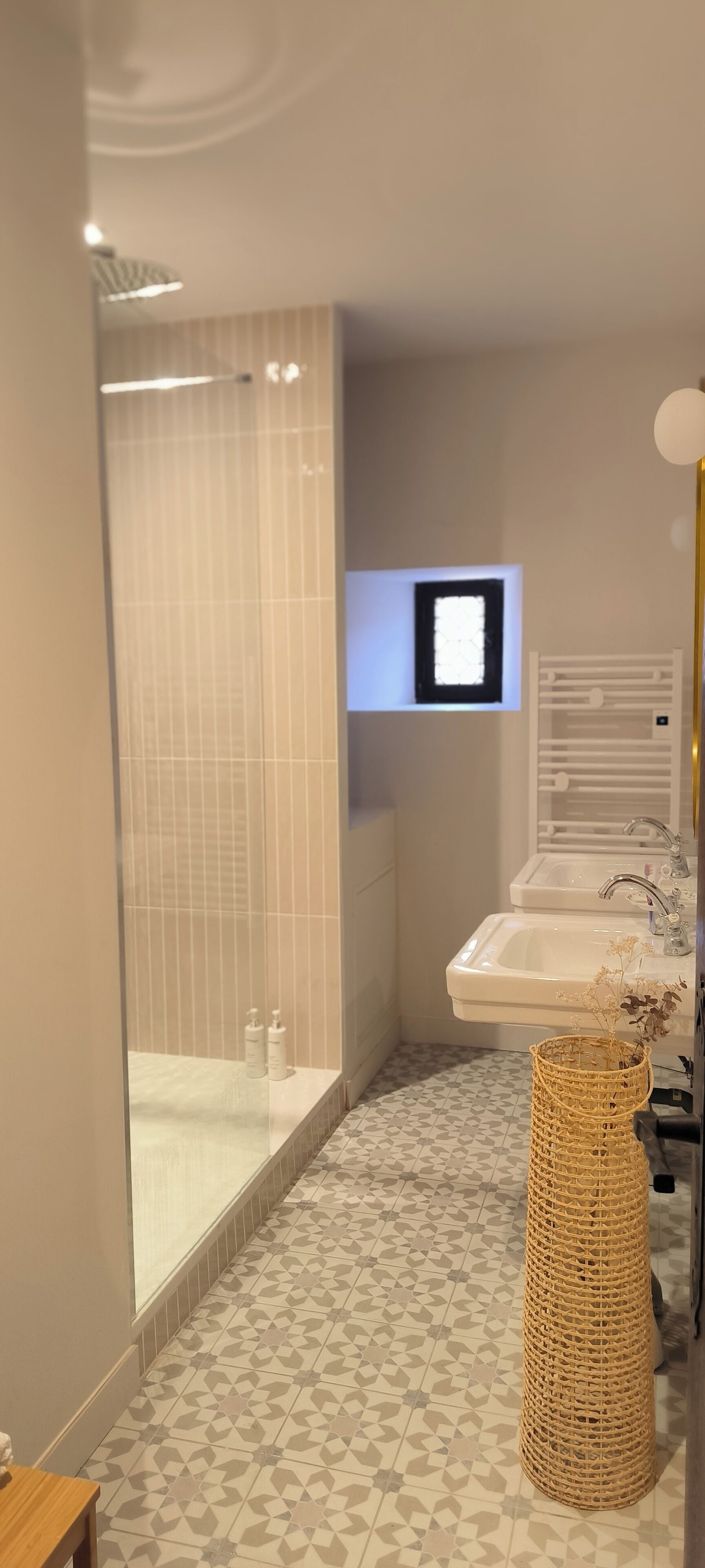 A modern bathroom with a glass shower enclosure, a sink with a mirror, and a decorative basket.