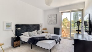 A modern bedroom with a bed, bedside tables, a desk, and a large window. - Jardin des plantes - First concierge service (Montpellier)