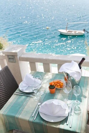 Una tavola imbandita per due con vista sul mare e una barca sullo sfondo.