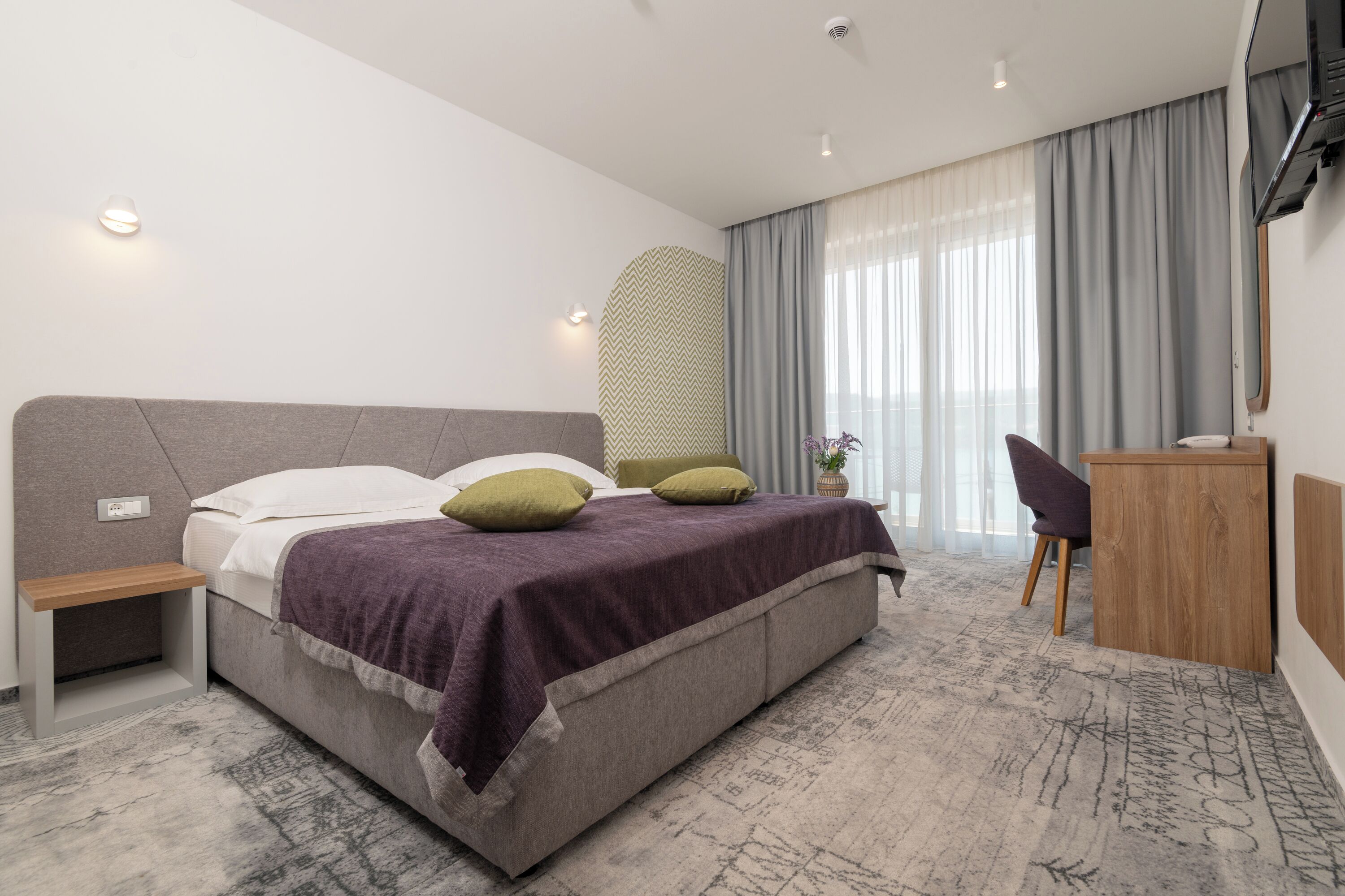 Una habitación de hotel moderna con una cama grande, un escritorio y una silla.