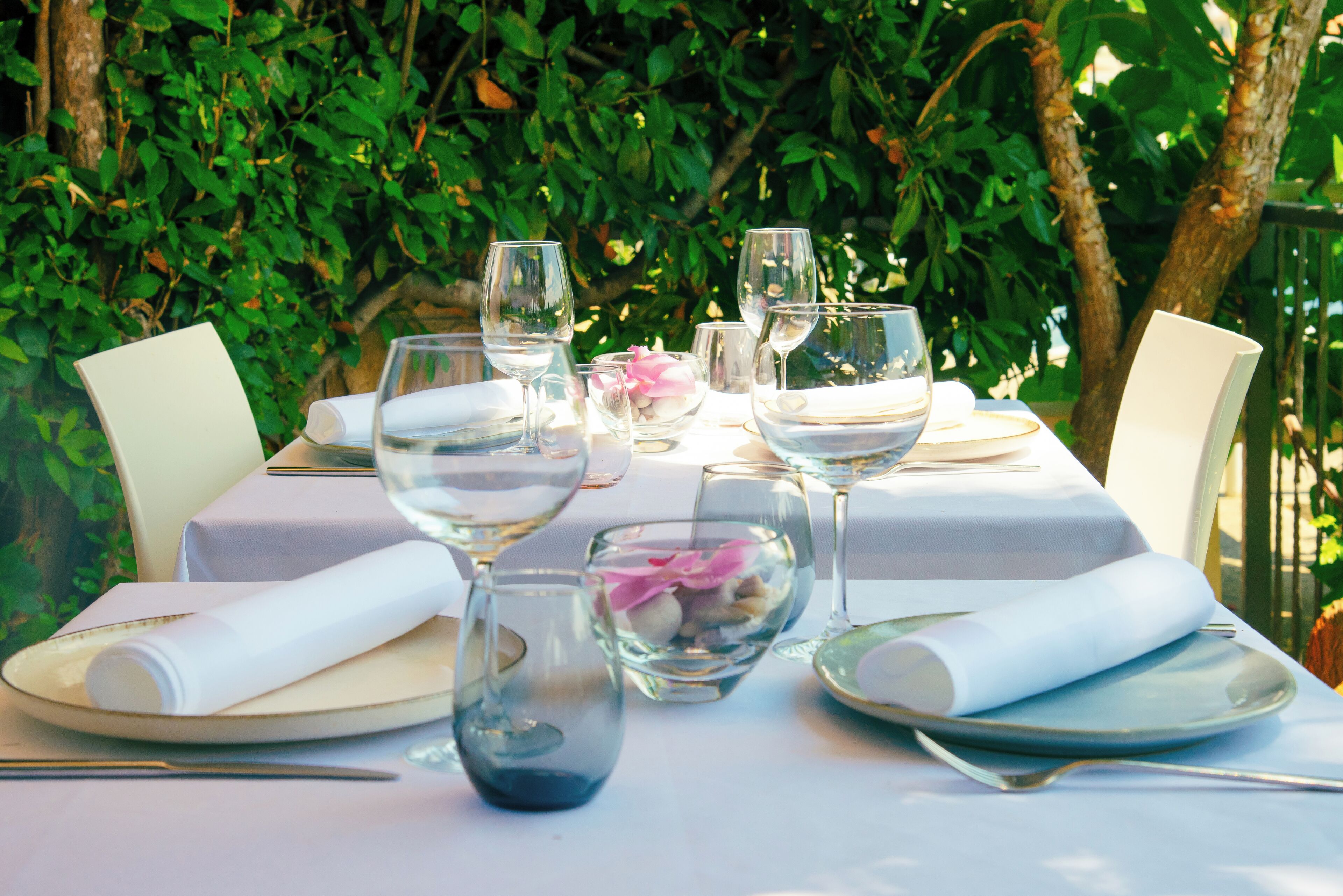 A table set for a meal with clear glassware, plates, and a bowl of flowers.