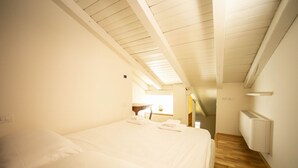 Een slaapkamer met een groot bed, een houten vloer, een radiator en een raam met natuurlijk licht.