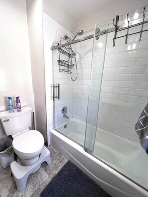 Une salle de bain moderne avec une douche à parois de verre, des toilettes blanches et une baignoire.
