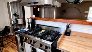 A modern kitchen with a gas stove, stainless steel appliances, and a wooden countertop.