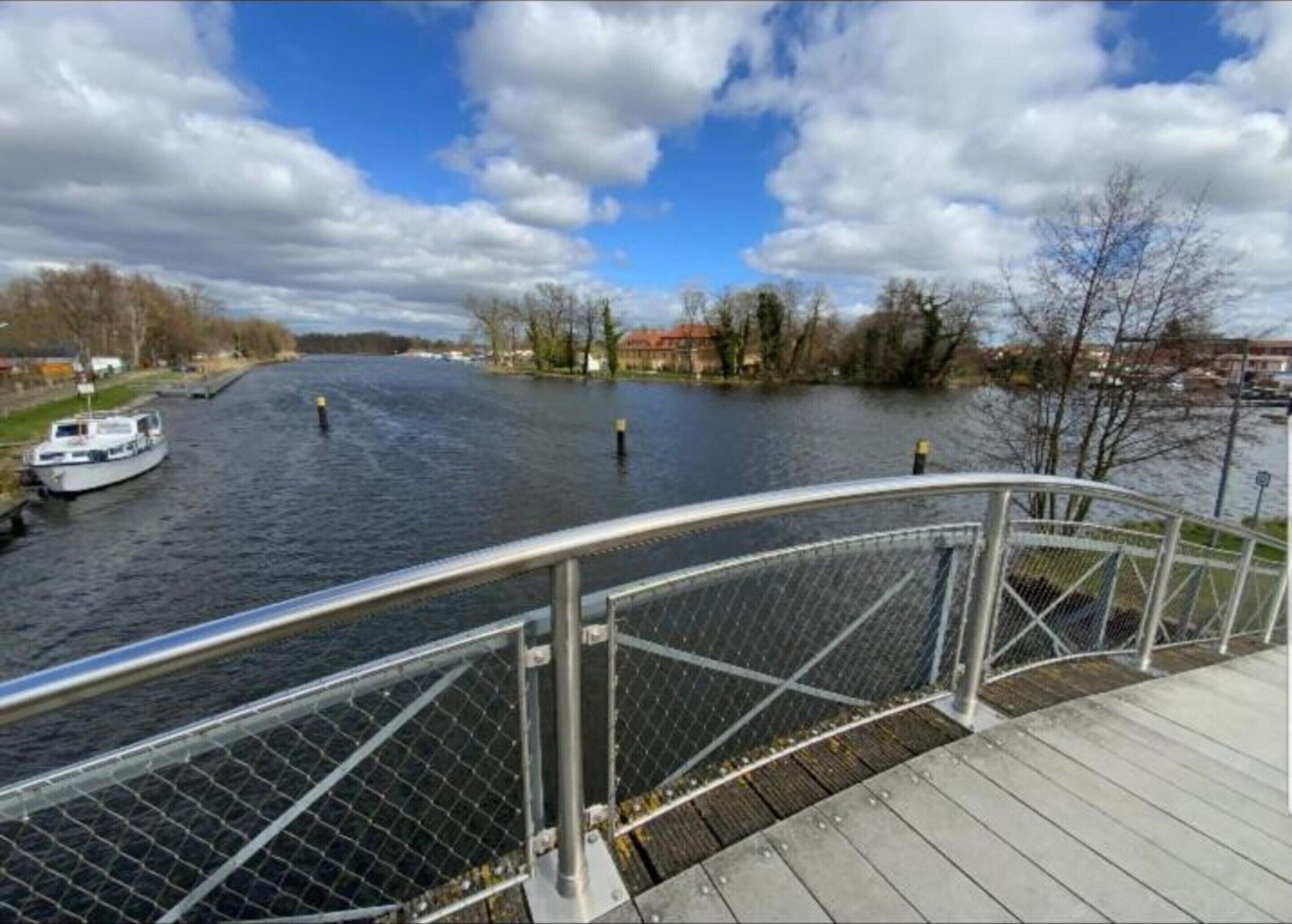 Une rivière avec un bateau, un pont et des bâtiments en arrière-plan.