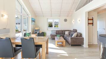 A spacious living area with a wooden dining table, black chairs, a brown sofa, and a coffee table.