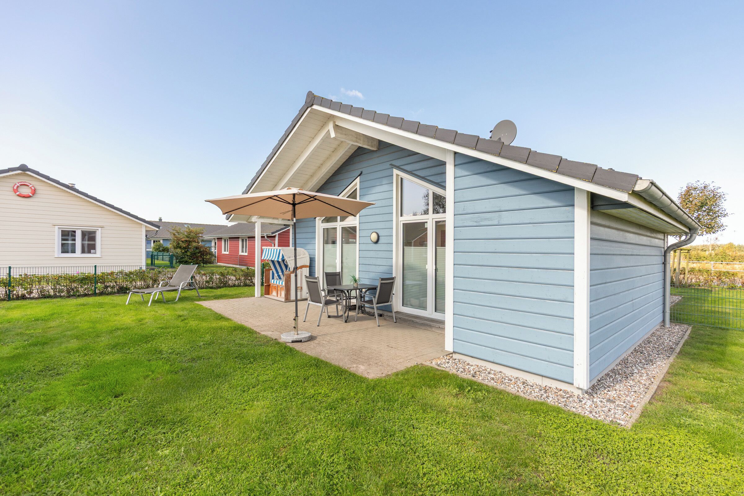 Een gelijkvloers huis met een overdekt terras, een gazon en een schotelantenne.