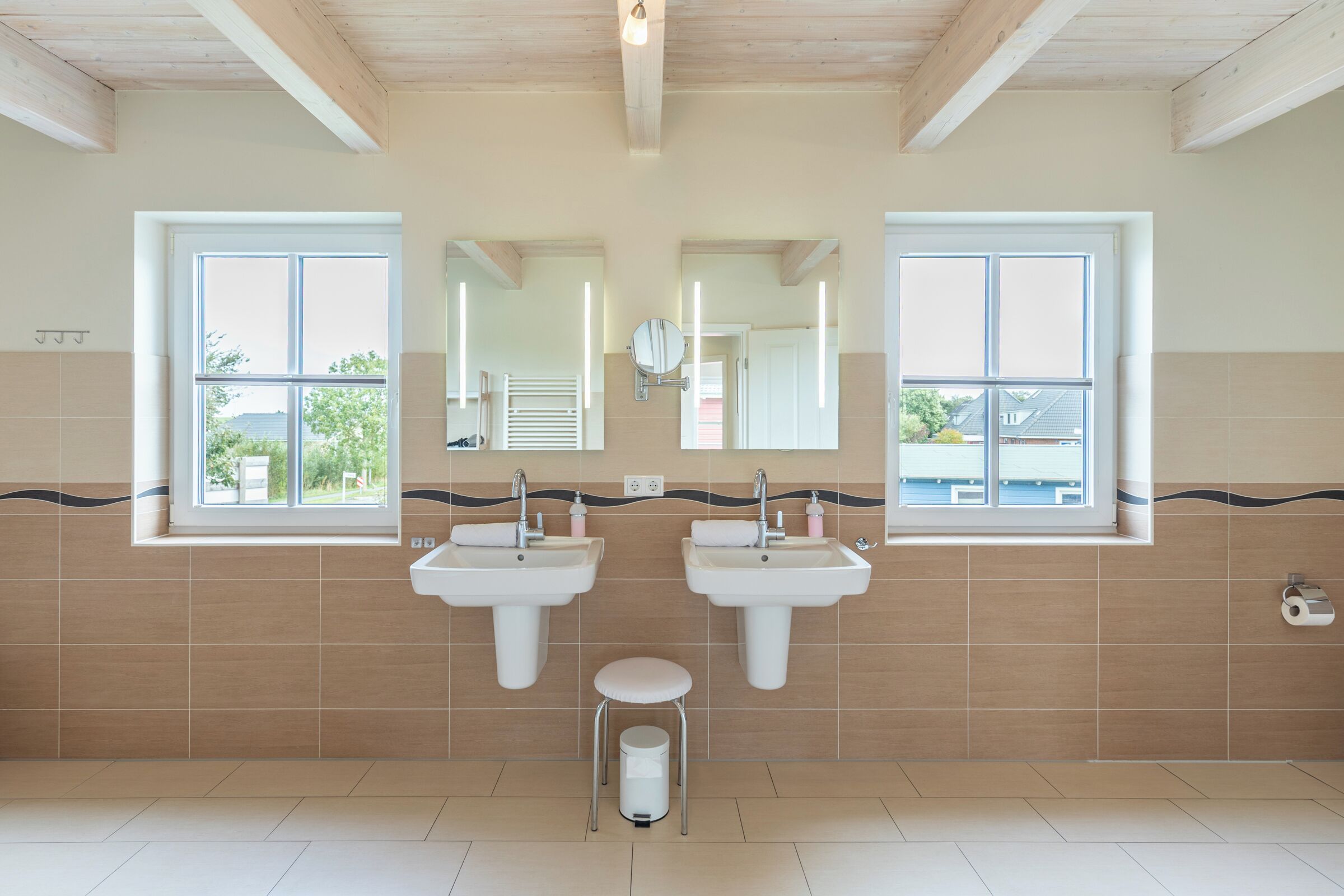 Un baño con dos lavamanos, un espejo y una ventana.