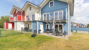 A two-story residential building with a balcony, a patio with outdoor furniture, and a fenced yard. - Vacation home "Fischerhuus" in Dagebüll for up to 7 people (Dagebüll)