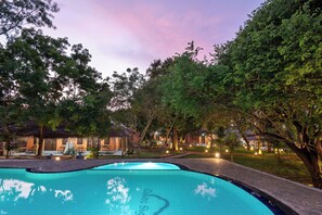 Una piscina con vistas despejadas del entorno, incluyendo árboles y un edificio con terraza.
