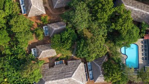 An aerial view of a resort with thatched-roof cabins, a swimming pool, and lush greenery. - La Cloudz Sigiriya (Sigiriya)