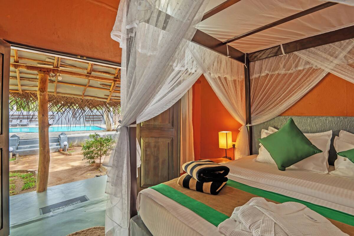 Una habitación con cama, mesita de noche, lámpara y vistas a un espacio exterior.