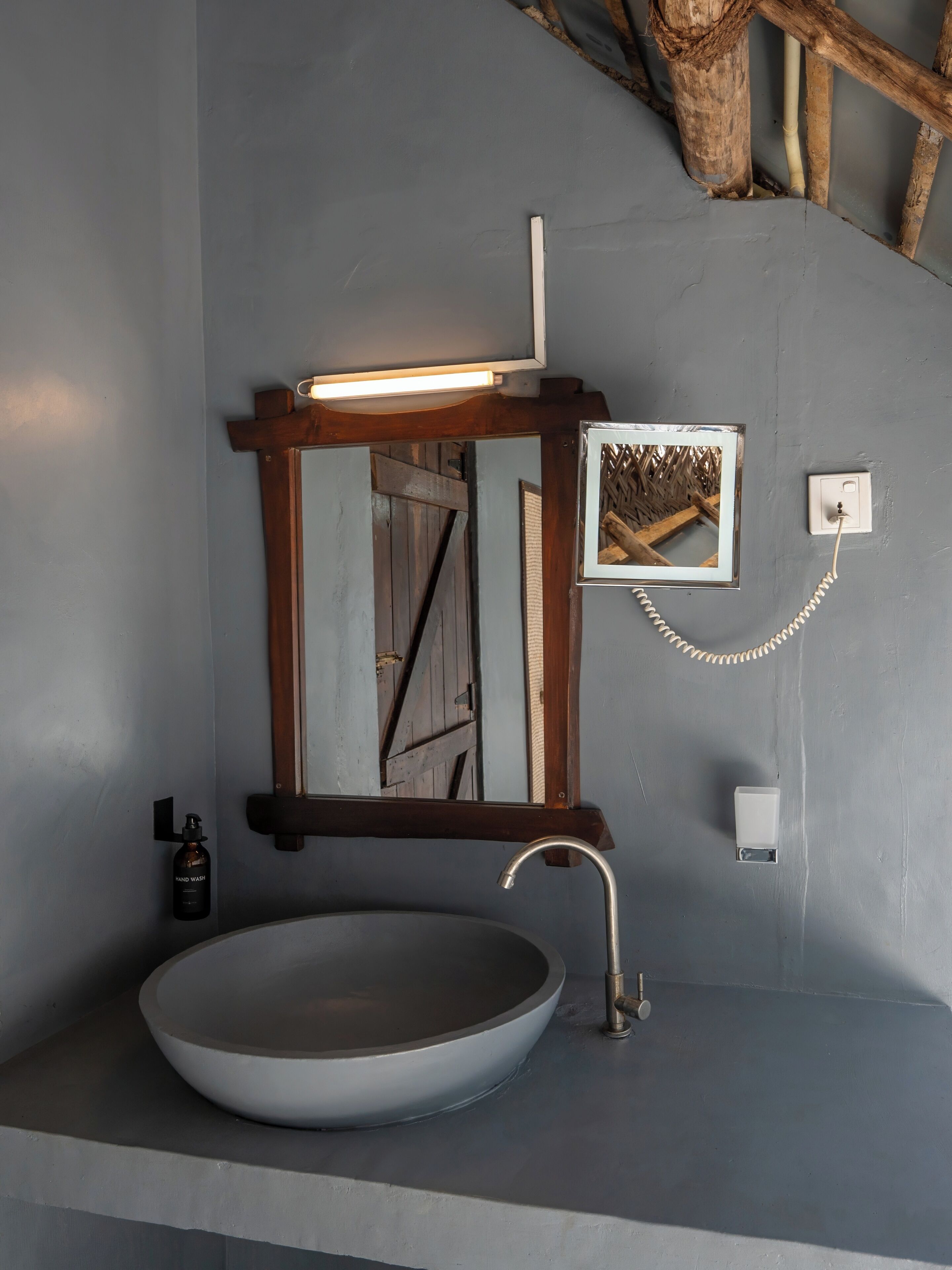 Ein Badezimmer mit einem großen, runden Waschbecken, einem spiegel mit Holzrahmen, einer Wandleuchte und einem gerahmten Bild.