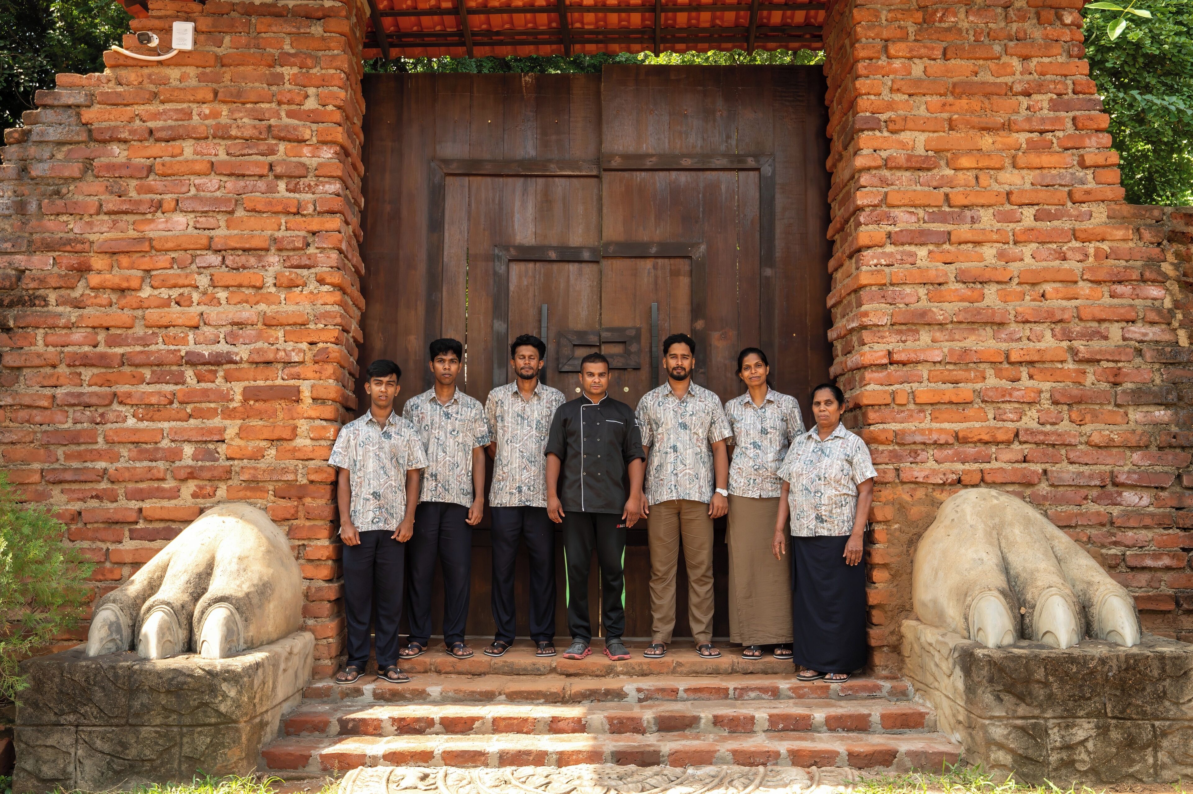 A group of people standing in front of a brick wall with a wooden door.