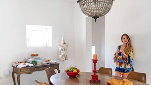 A dining area with a chandelier, a mannequin, and a table set with food and drinks. - Reggia del Saraceno – Luxury House in the Heart of Ortigia (Siracusa)