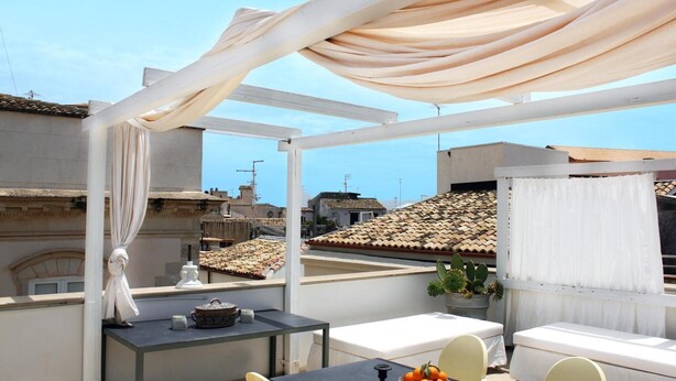 A rooftop terrace with a table, chairs, and a view of the cityscape. - Reggia del Saraceno – Luxury House in the Heart of Ortigia (Siracusa)
