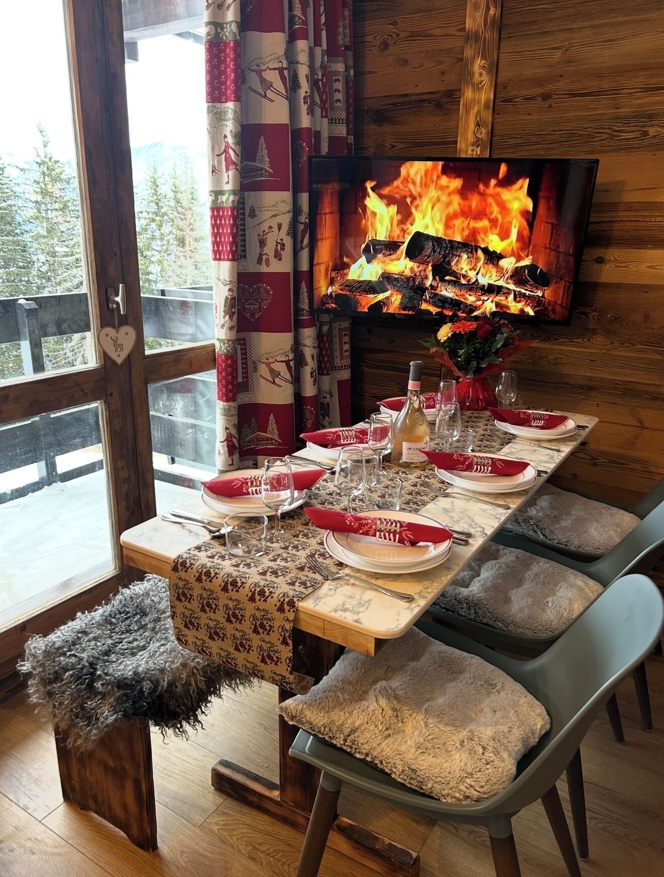 A cozy dining area with a fireplace, a TV mounted on the wall, and a view of the outdoors.