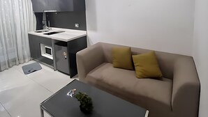 Ein modernes Wohnzimmer mit einer Couch, einem Couchtisch und einer Küchenzeile mit Spüle und Schränken.