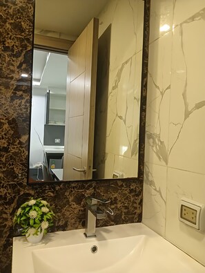 Ein Badezimmer mit Marmorwaschbecken, einem Spiegel und einer Topfpflanze.