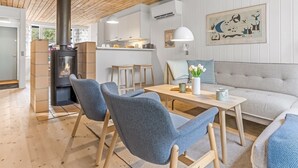 A modern living room with a fireplace, grey upholstered chairs, a sofa, and a dining table. - "Catha" - 200m from the sea by Interhome (Væggerløse)
